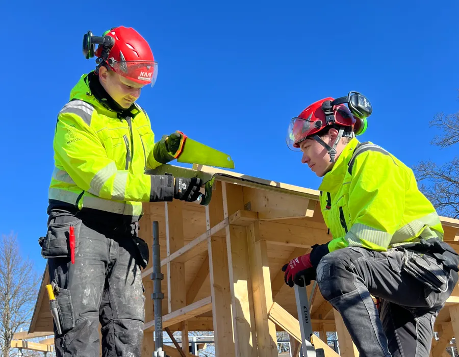 Två unga killar bygger på ett hus.