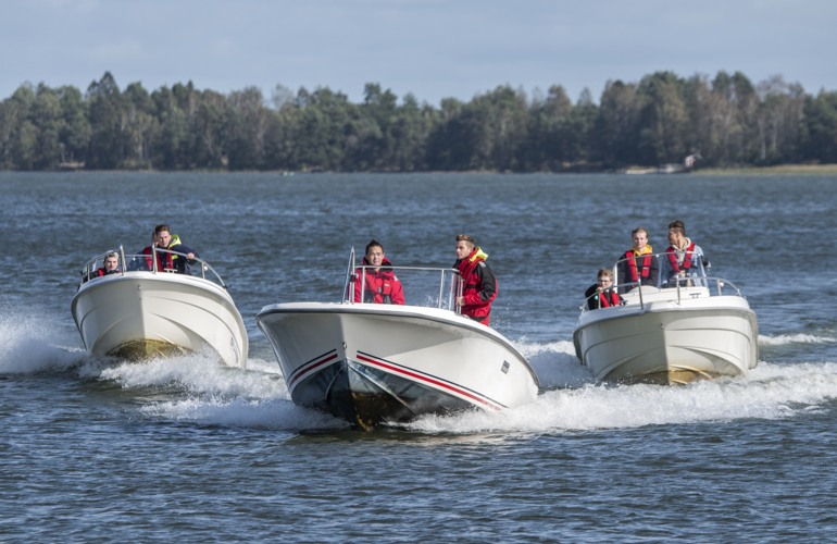 Tre motorbåtar med elever i som åker på en sjö